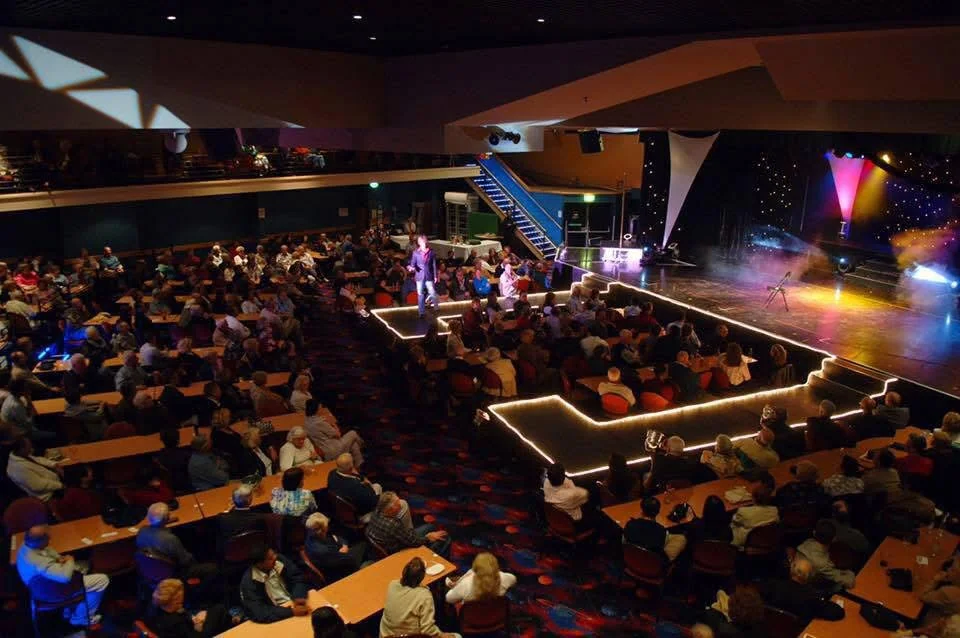 A theatre audience looking toward a brightly lit stage